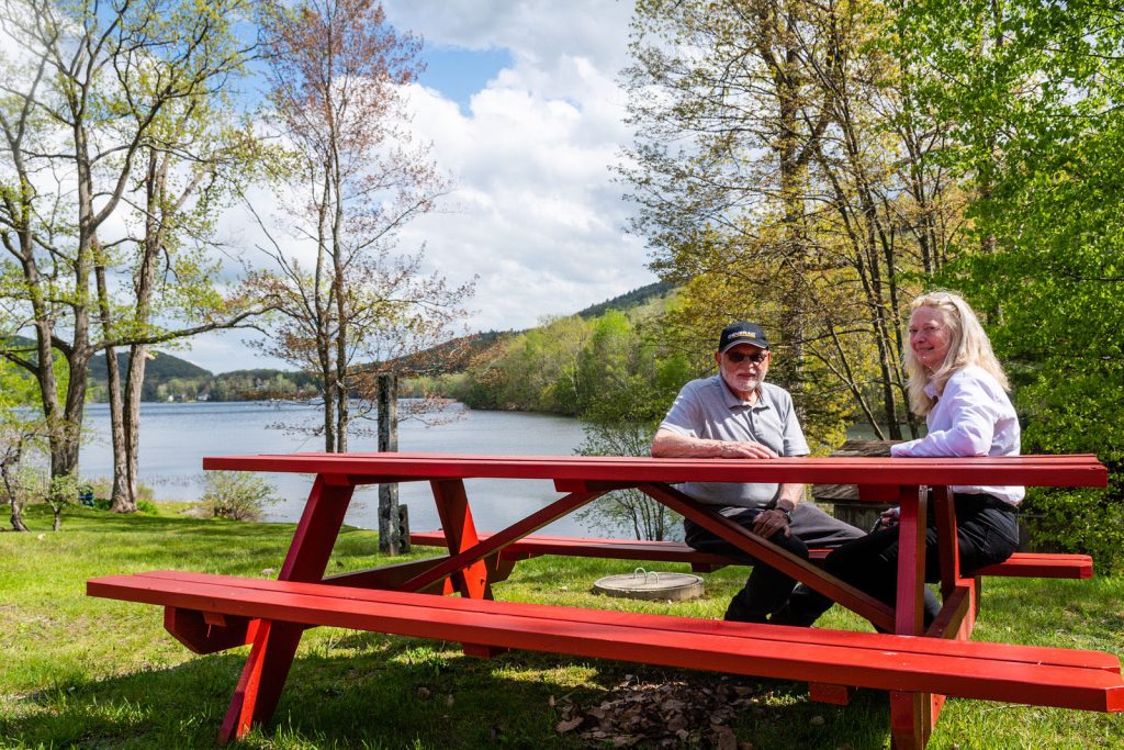 Couple sitting on red bench by lake						
